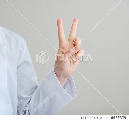 一名身穿白大褂的女子做出和平手勢,表示勝利。 一名身穿白大褂的女子做出和平手勢,表示勝利。 6677859