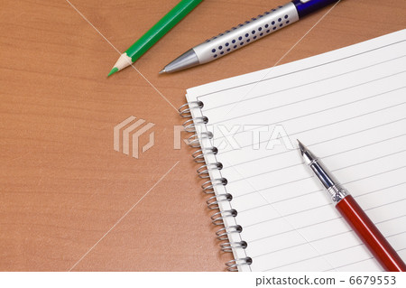ink pen and pencil near notebook on wood 6679553