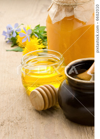 honey and flowers in glass jars on wood 6682010