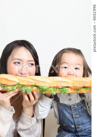 Parent and child eating baguet sandwich Parent and child eating baguet sandwich 6682996