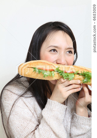 A woman eating a baguet sandwich A woman eating a baguet sandwich 6683009