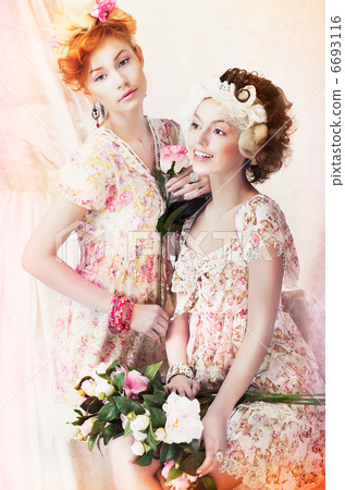 Freshness. Two Young Pretty Women in Classic Vintage Dresses with Flowers. Pin-up Style Freshness. Two Young Pretty Women in Classic Vintage Dresses with Flowers. Pin-up Style 6693116