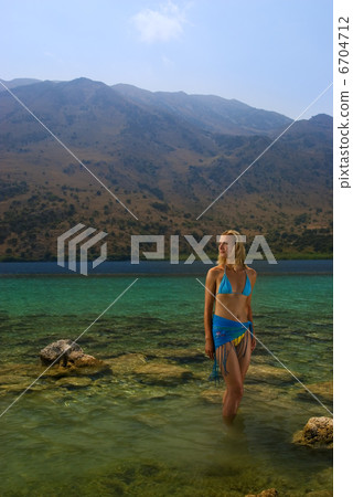 Beautiful blond girl standing in crystal clear water 6704712