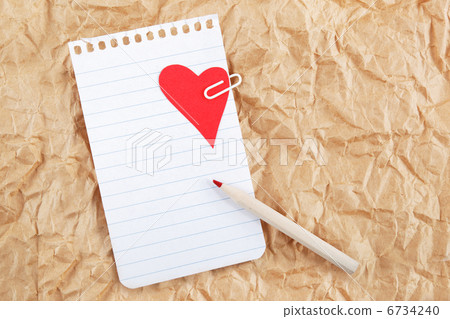 Sheet of notebook with a heart and pencil on crumpled paper. Val 6734240