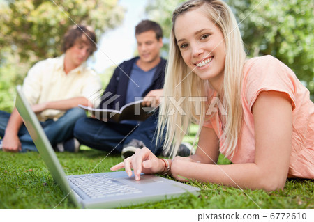 Portrait of a girl using a laptop while lying in a park 6772610