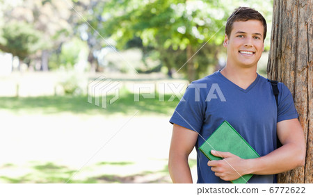 Portrait of a smiling muscled student holding a textbook Portrait of a smiling muscled student holding a textbook 6772622