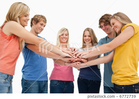 Low angle shot of friends smiling and looking at their hands sta Low angle shot of friends smiling and looking at their hands sta 6772739