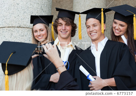 Close-up of a graduate taking a picture of her friend Close-up of a graduate taking a picture of her friend 6773157