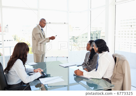 Businessman pointing to something on the flipchart to explain th Businessman pointing to something on the flipchart to explain th 6773325