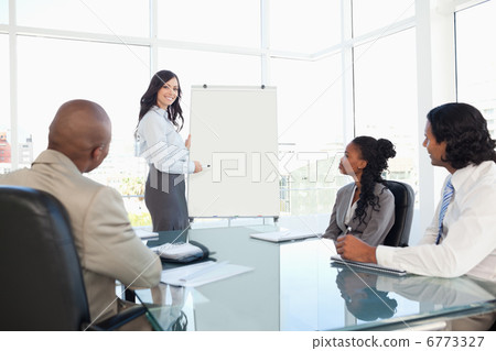 Businesswoman giving a presentation while her co-workers are lis 6773327