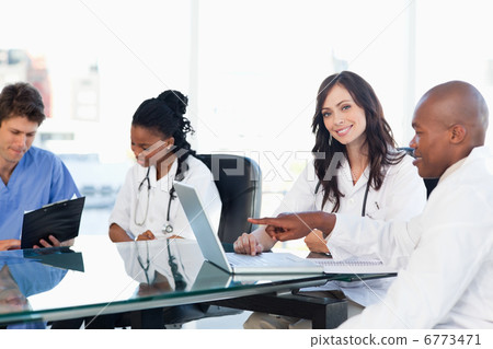 Two smiling medical interns working at the computer near colleag 6773471