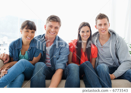 Smiling group on the couch looking at the camera while leaning f Smiling group on the couch looking at the camera while leaning f 6773543