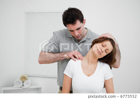 Serious osteopath palpating the trapezius of a woman 6773552