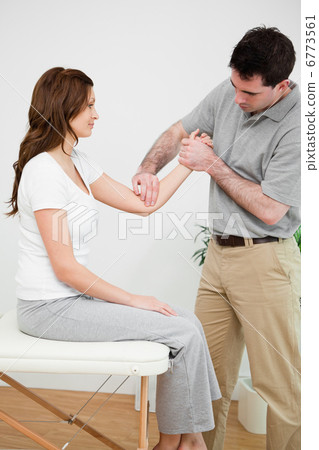 Serious physiotherapist touching the elbow of a woman Serious physiotherapist touching the elbow of a woman 6773561