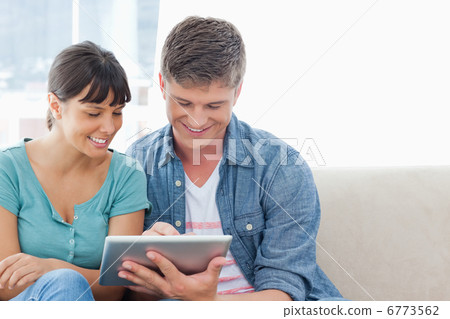 A couple sitting and using a tablet pc together A couple sitting and using a tablet pc together 6773562