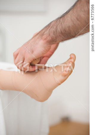 Doctor bandaging an ankle Doctor bandaging an ankle 6773566