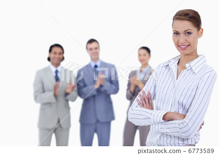 Close-up of a woman crossing her arms with business people appla 6773589