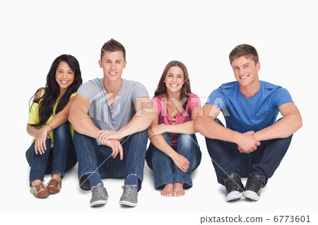 Smiling group sitting on the ground with their hands on their le Smiling group sitting on the ground with their hands on their le 6773601