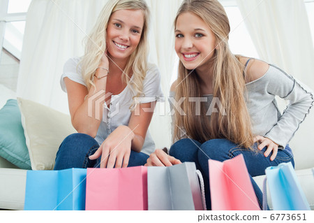 Smiling girls looking at the camera with bags by their feet Smiling girls looking at the camera with bags by their feet 6773651