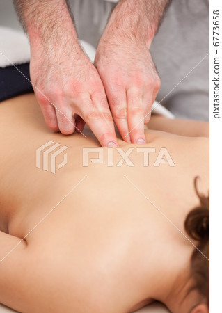 Osteopath massaging a woman in the middle of her back Osteopath massaging a woman in the middle of her back 6773658