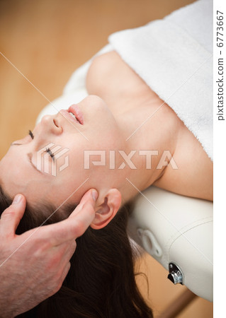 Woman lying on the back while being massaged on her head 6773667