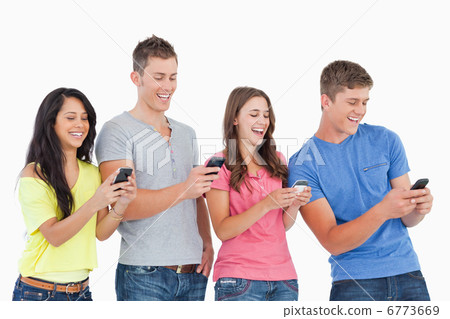 Four laughing friends sending texts on their phones 6773669