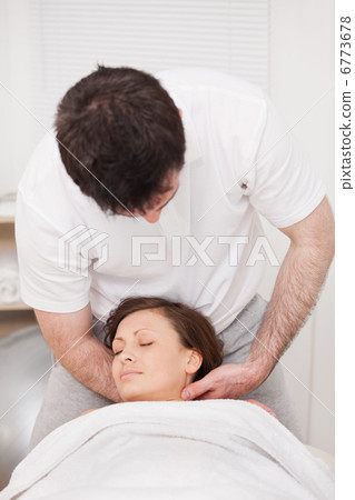 Therapist massaging the neck of a woman while holding her head 6773678