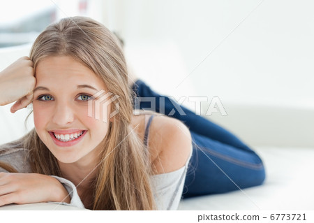 Smiling girl lying on the couch as she looks at the camera Smiling girl lying on the couch as she looks at the camera 6773721