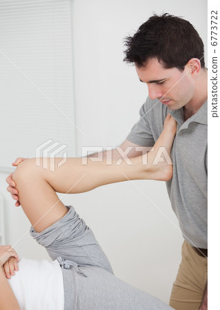 Woman putting her leg on the chest of doctor while stretching Woman putting her leg on the chest of doctor while stretching 6773722