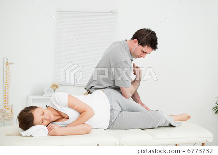 Chiropractor massaging the thigh of his patient while using his 6773732