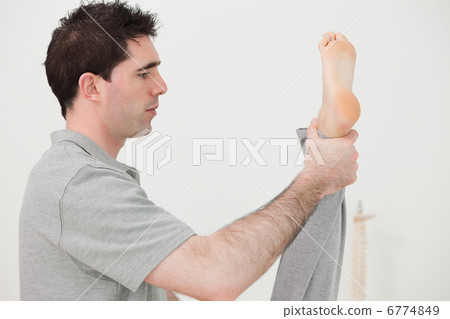 Brown-haired chiropractor stretching the leg of his patient Brown-haired chiropractor stretching the leg of his patient 6774849