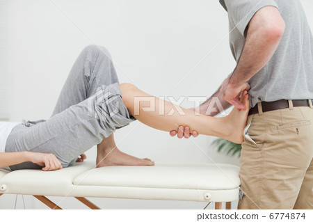 Close-up of a physiotherapist stretching the foot of a patient Close-up of a physiotherapist stretching the foot of a patient 6774874