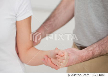 Close-up of a man examining the elbow of a woman Close-up of a man examining the elbow of a woman 6774886
