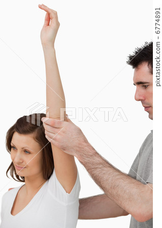 Serious doctor raising the arm of a woman Serious doctor raising the arm of a woman 6774891
