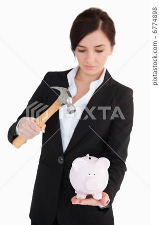 Woman in suit going to break a piggy-bank 6774898