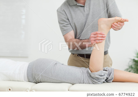 Woman lying forward while a physiotherapist examining her leg Woman lying forward while a physiotherapist examining her leg 6774922