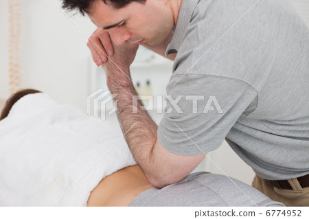 Woman lying forward while a physiotherapist is massaging her bac Woman lying forward while a physiotherapist is massaging her bac 6774952