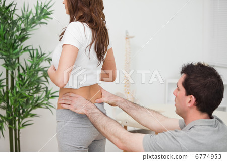 Doctor sitting while examining the hips of a woman Doctor sitting while examining the hips of a woman 6774953