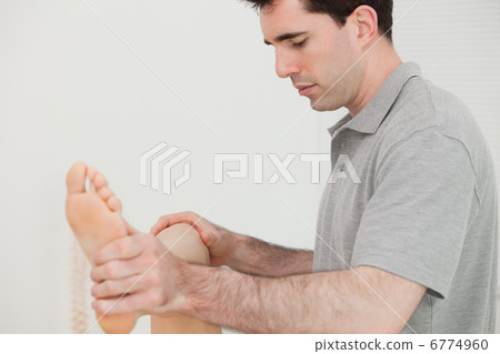 Physio moving his the leg of his patient Physio moving his the leg of his patient 6774960