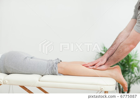 Close up of a masseur massaging the calves of a woman 6775087