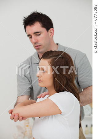 Serious brunette doctor stretching the arm of a woman 6775088