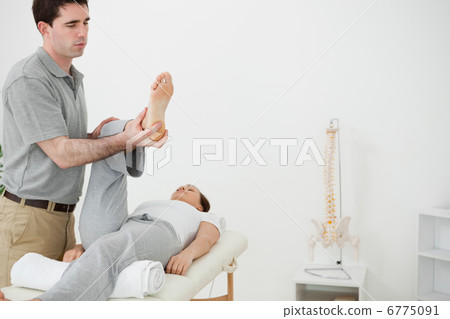 Brunette physiotherapist manipulating the leg of a woman 6775091