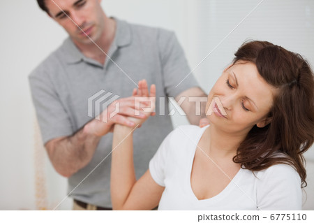 Woman sitting while being stretched by a physiotherapist 6775110