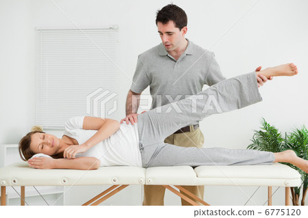 Serious practitioner rising the leg of his patient Serious practitioner rising the leg of his patient 6775120