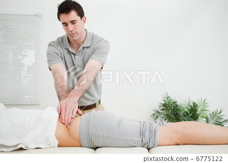 Masseur standing while massaging the back of his patient 6775122