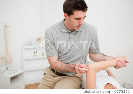 Serious brunette physiotherapist holding the arm of a woman Serious brunette physiotherapist holding the arm of a woman 6775151