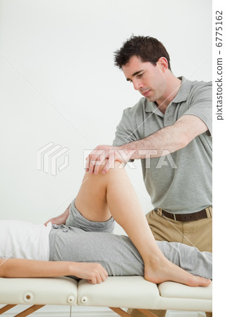 Serious physiotherapist stretching a leg while standing Serious physiotherapist stretching a leg while standing 6775162