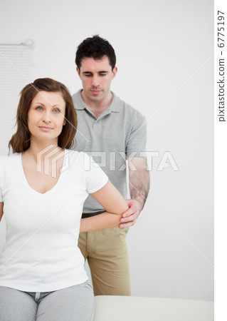Serious osteopath holding the elbow of a patient Serious osteopath holding the elbow of a patient 6775197