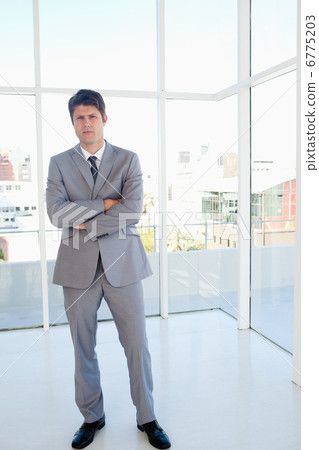 Stern businessman standing in a well-lit area Stern businessman standing in a well-lit area 6775203