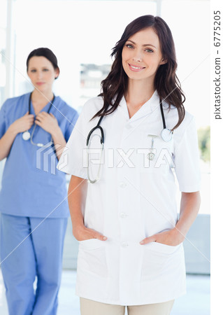 A nurse standing upright while her colleague is standing behind A nurse standing upright while her colleague is standing behind 6775205
